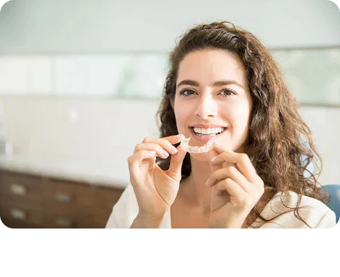 A girl holding dental retainers in her hand.