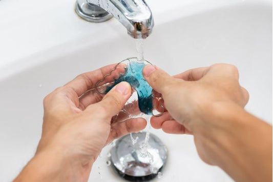 A man rinsing his dental retainer with water
