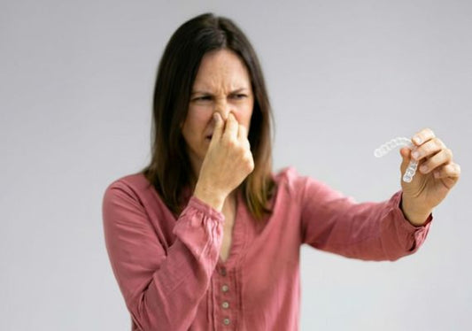A woman holding smelly aligners and holding her breath