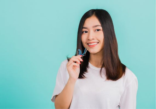 A girl holding Hawley retainers in her hand.