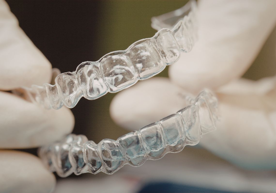 A professional wearing gloves holding clear aligners