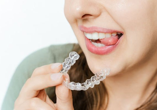 A woman holding clear aligners for teeth straightening without a dentist.
